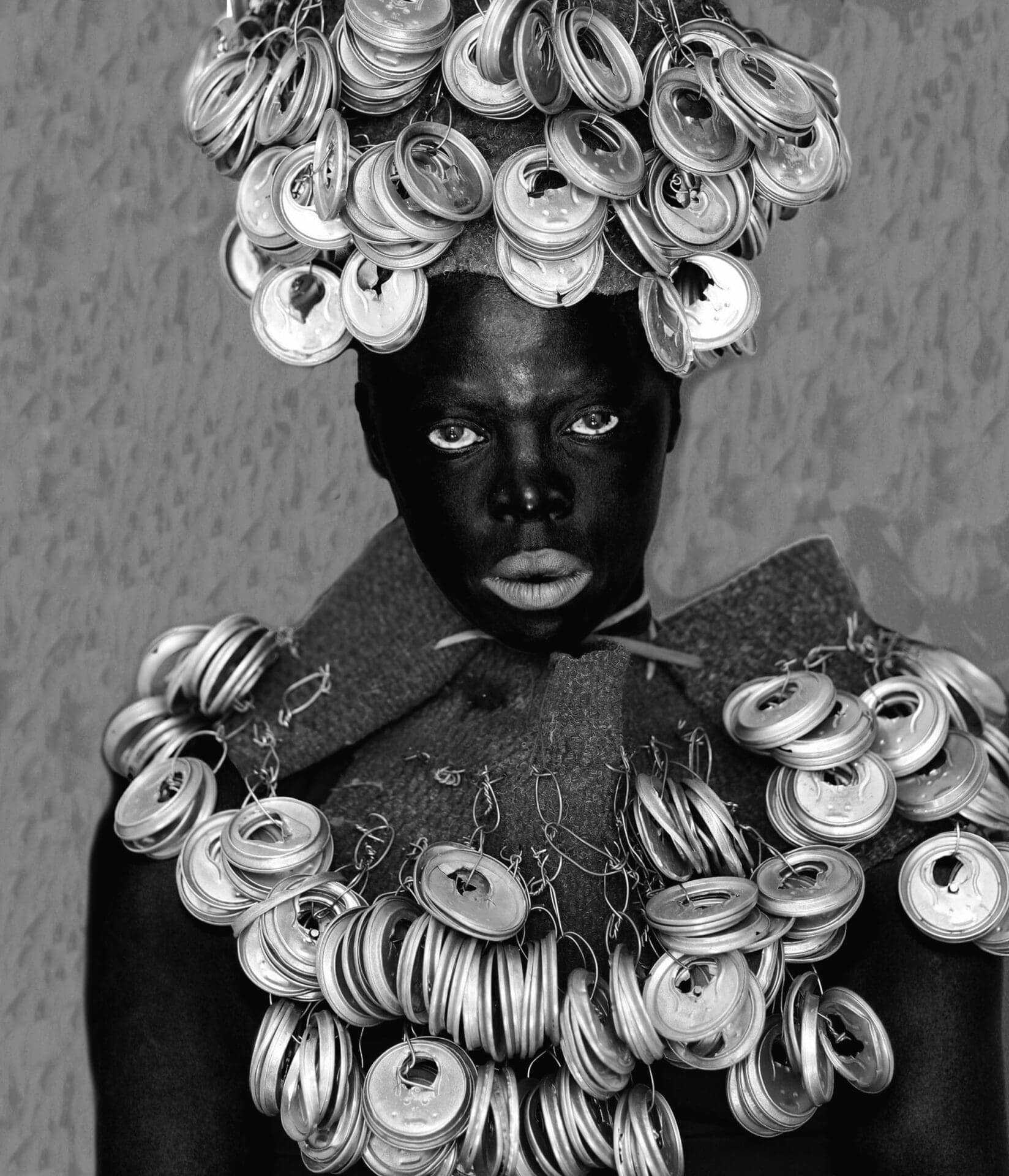 a black and white image of the artist wearing a garment with dozens of metal tops
