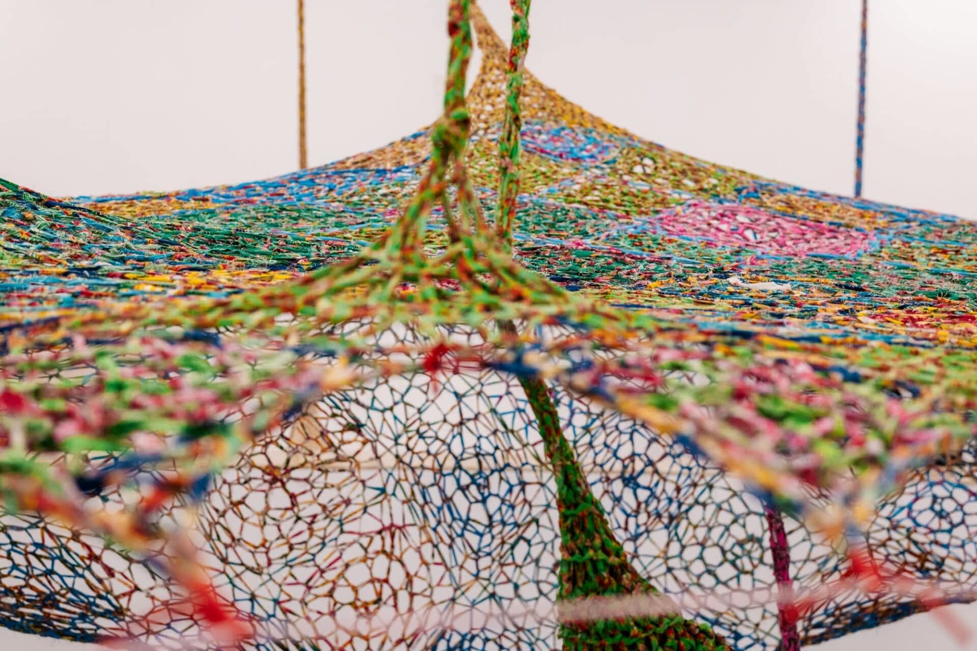 a detail of colorful strips of chintz fabric crocheted into a suspended sculpture
