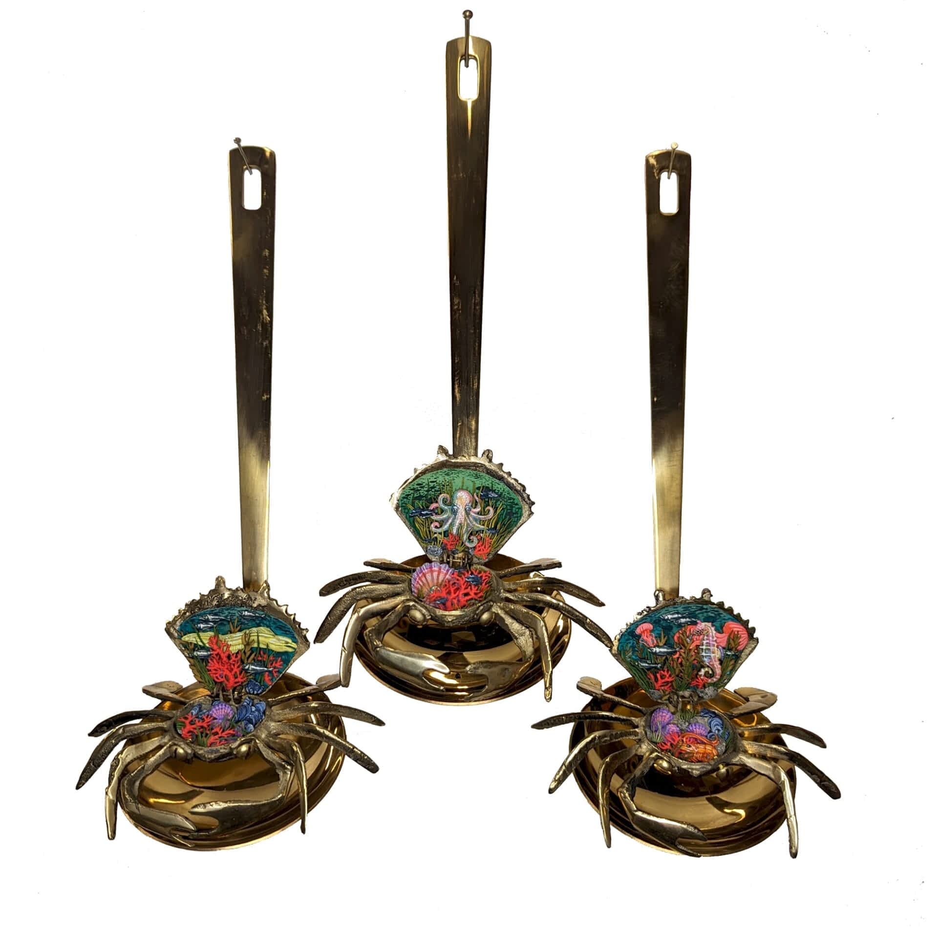 three brass ladle-like utensils with brass crab ornaments that open up to reveal miniature dioramas of sea-themed scenes inside