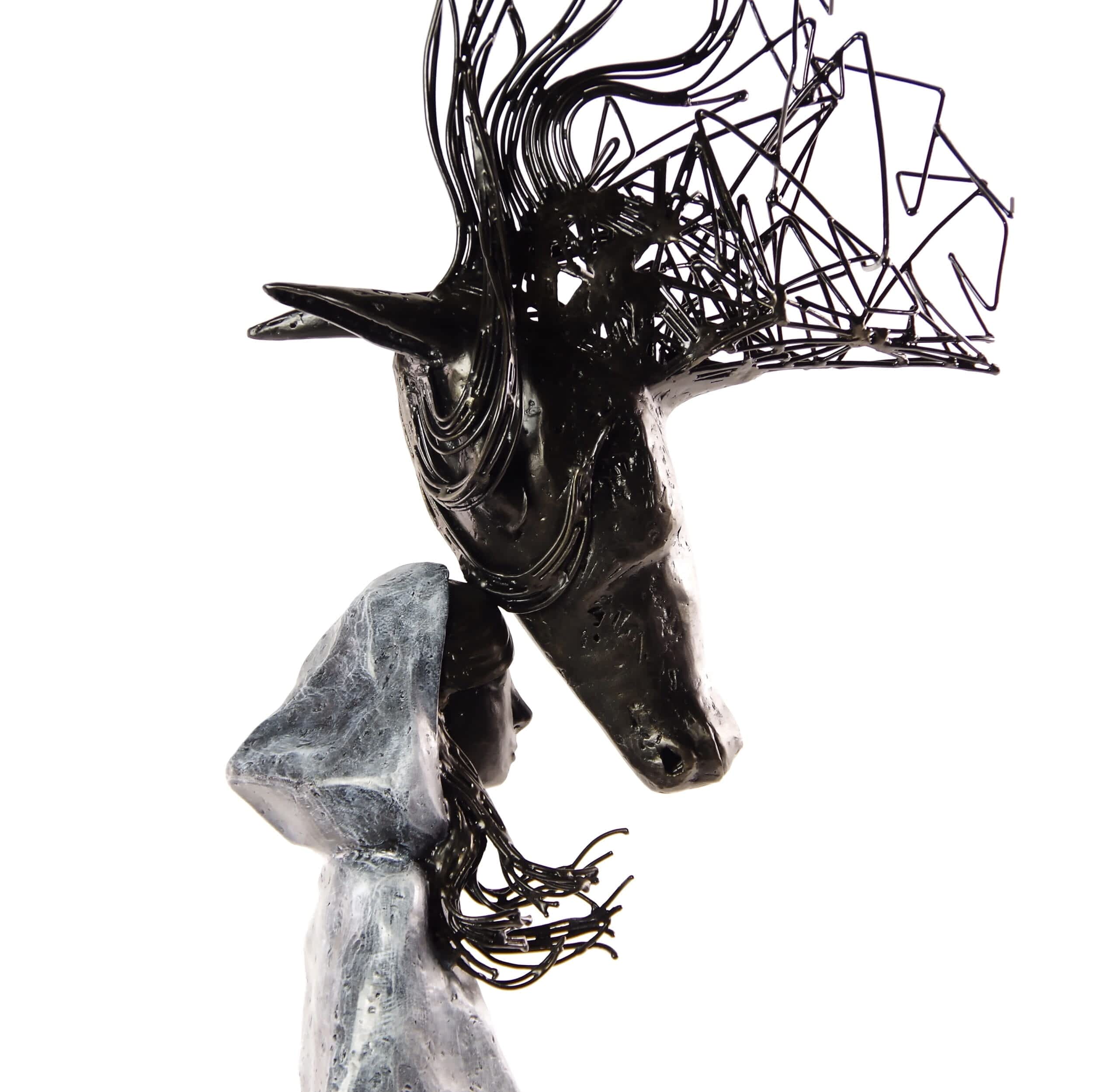 an iron sculpture of a young girl with a hood, touching foreheads with a large horse, which gradually fades into lines