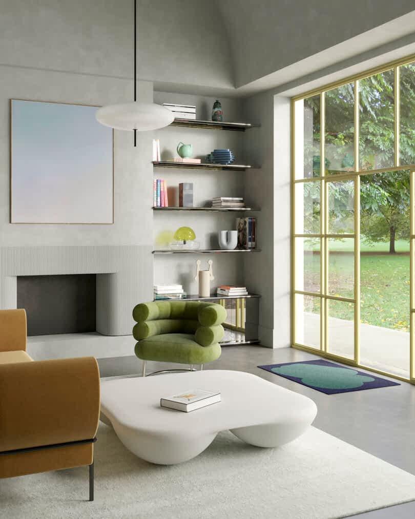 Modern living room with large windows overlooking a garden, featuring a green armchair, beige sofa, fireplace, and built-in shelves