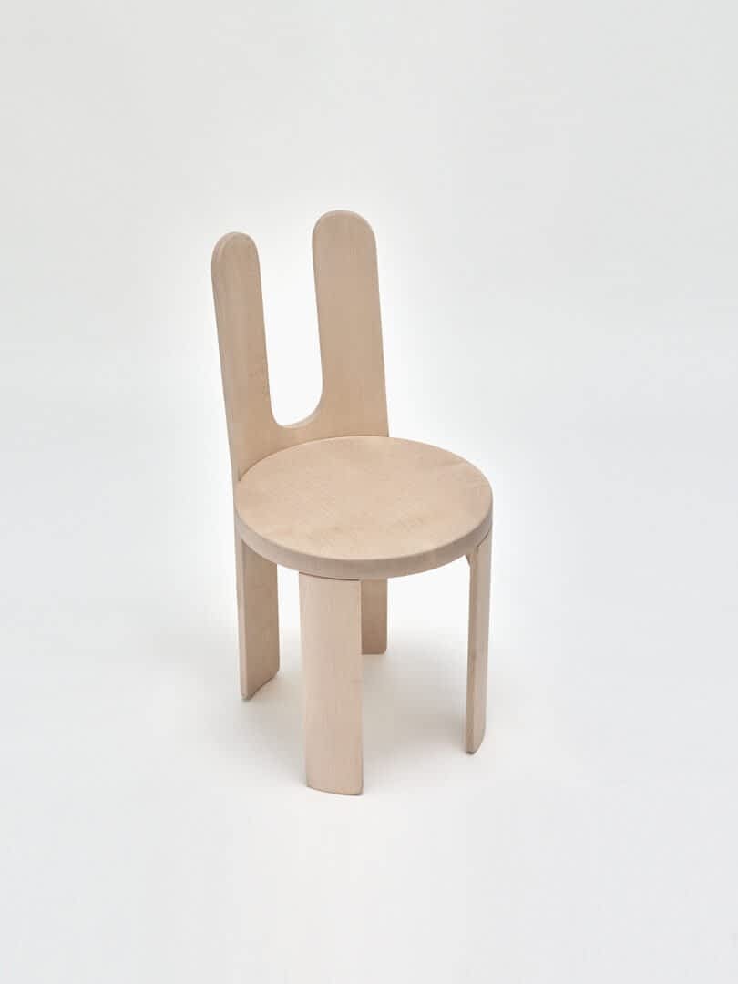A modern chair with a light wood finish and a unique, dual backrest design.