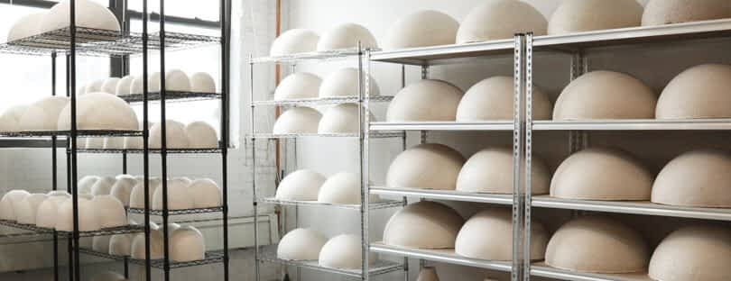 Shelves filled with large, dome-shaped MushLume Lighting fixtures are organized in rows inside an industrial-style room.