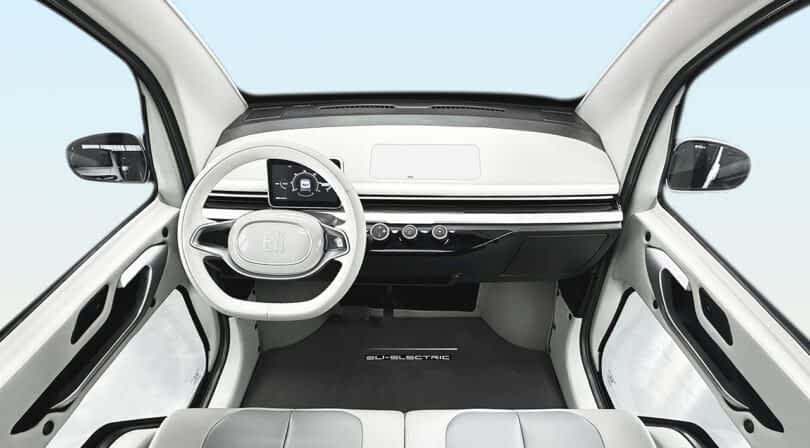 Interior view of the Eli ZERO micro EV, showing a minimalist dashboard with a digital display and a round steering wheel.