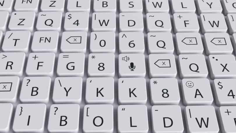 A close-up view of a tactile keyboard with white keys displaying various symbols, letters, and icons, including a microphone icon in the center.