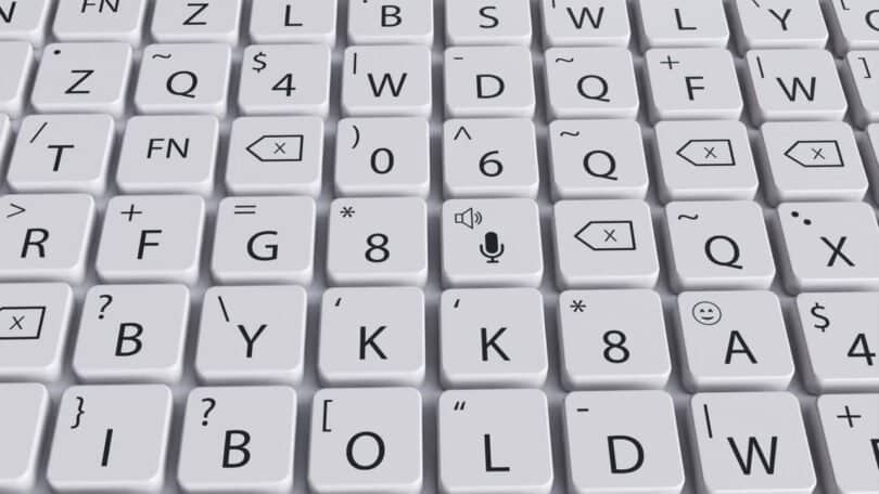A close-up view of a tactile keyboard with white keys displaying various symbols, letters, and icons, including a microphone icon in the center.