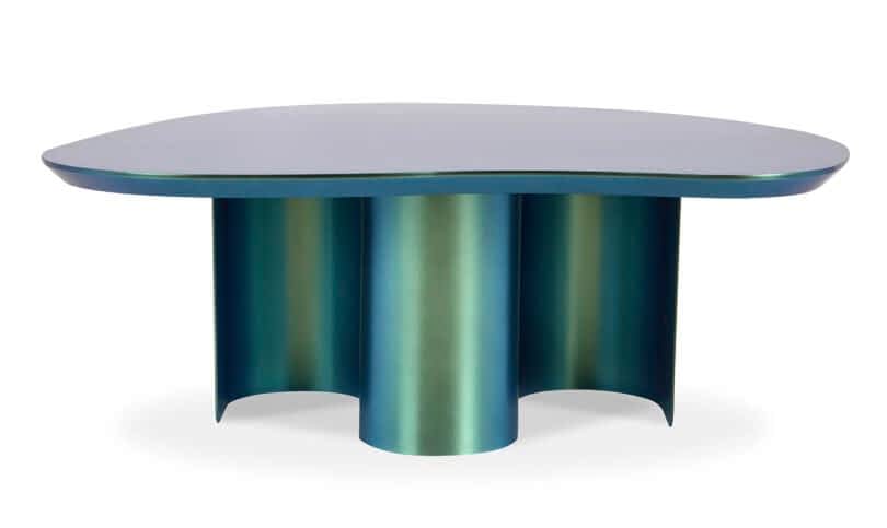 A modern iridescent table with an irregularly shaped top and cylindrical legs.