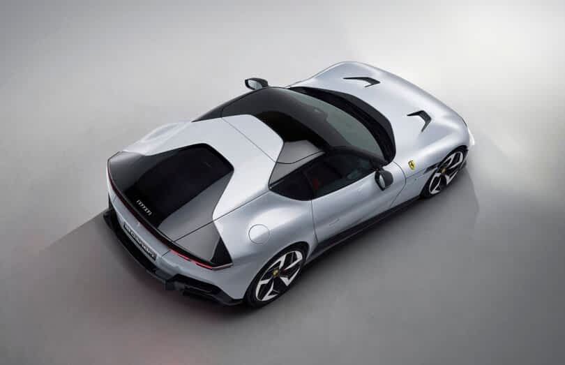 Top-down view of a silver Ferrari 12Cilindri sports car on a light gray surface, showcasing its sleek design and aerodynamic shape.