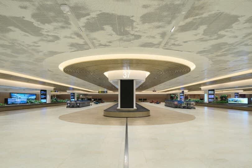 Modern airport baggage claim area with circular ceiling design and carousel number 37 in the center.