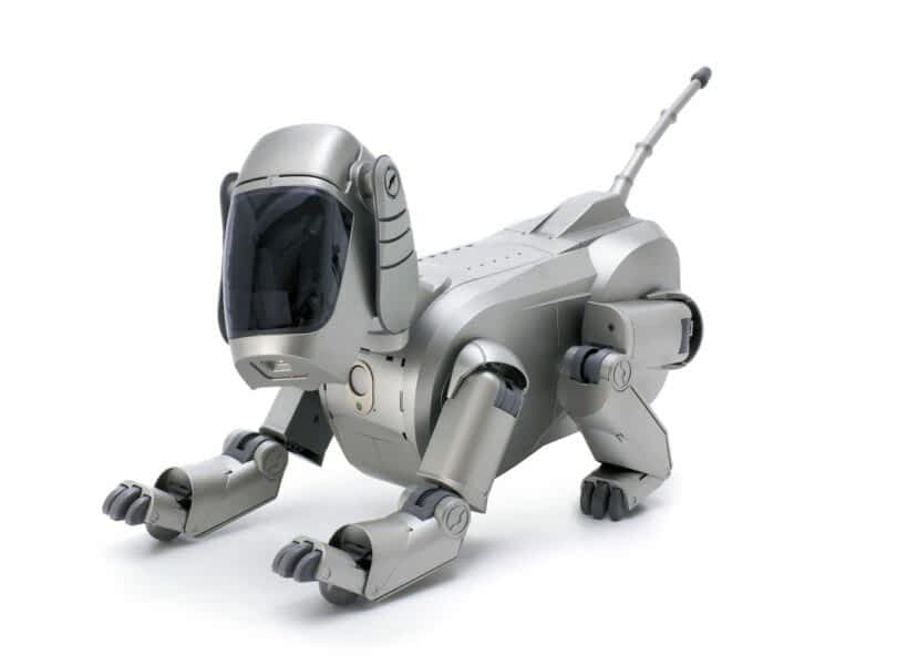A silver robotic dog with a sleek design, featuring a large dark visor for a face and articulated limbs, posed on a white background