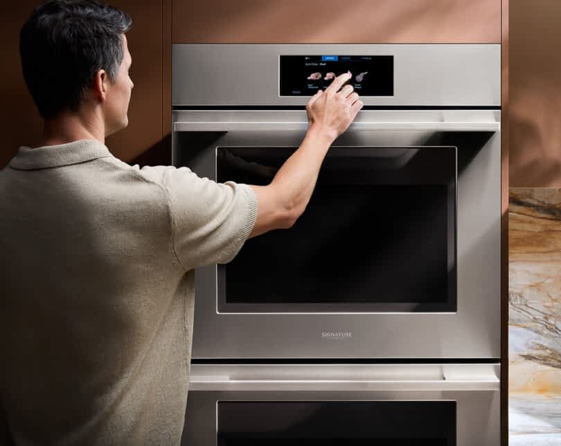 Man reaching out to operate touch controls of the SKS Transitional Double Wall Oven
