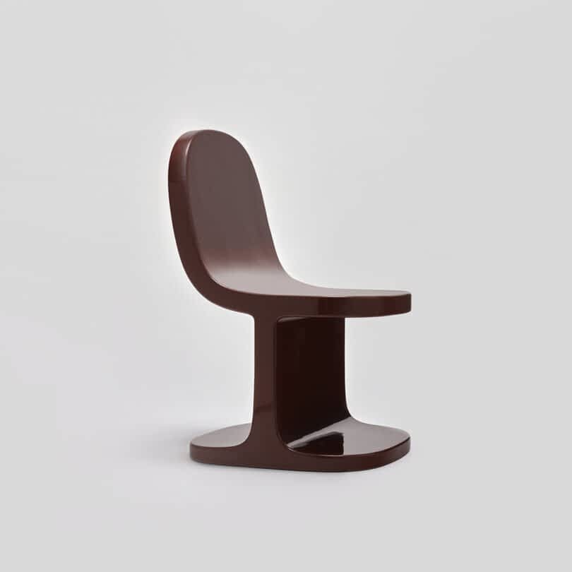 Brown modern chair against a neutral gray background.