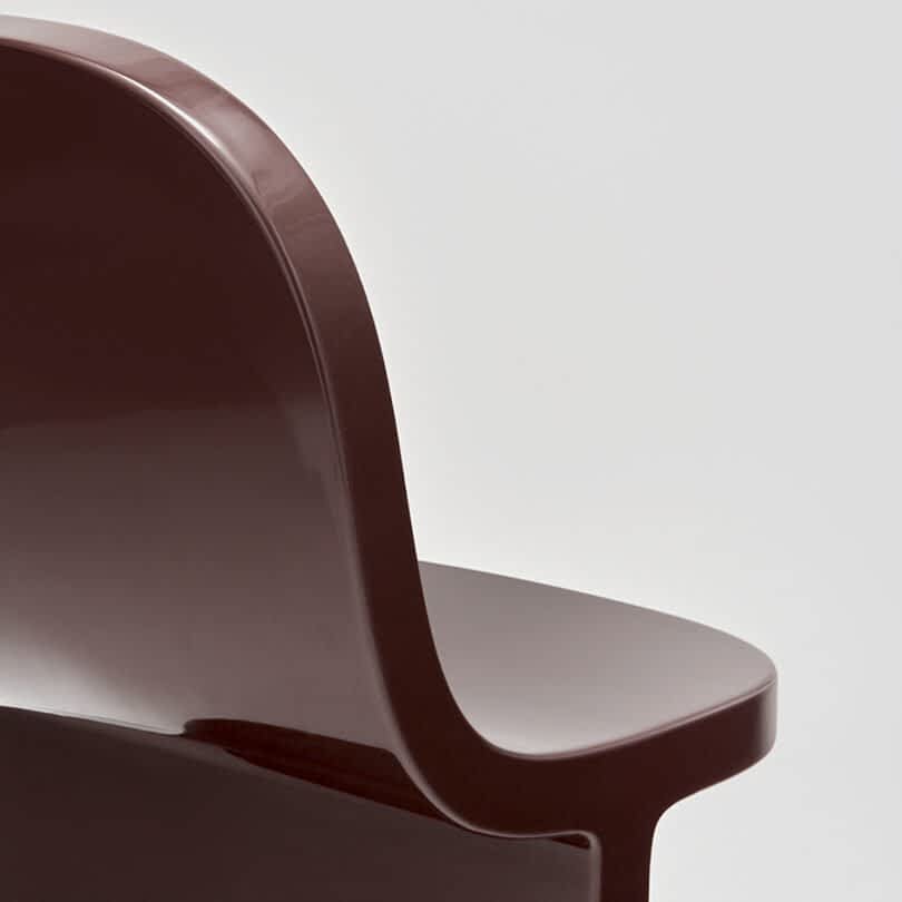 Close-up of a brown modern chair against a neutral gray background.