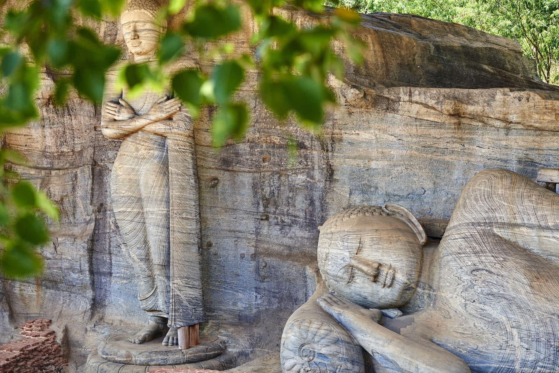 Monumental Buddha statues at the Gal Vihara temple complex, Polonnaruwa, Sri Lanka. Monumental Buddha statues viewed through the leaves at the Gal Vihara temple complex, Polonnaruwa, Sri Lanka.