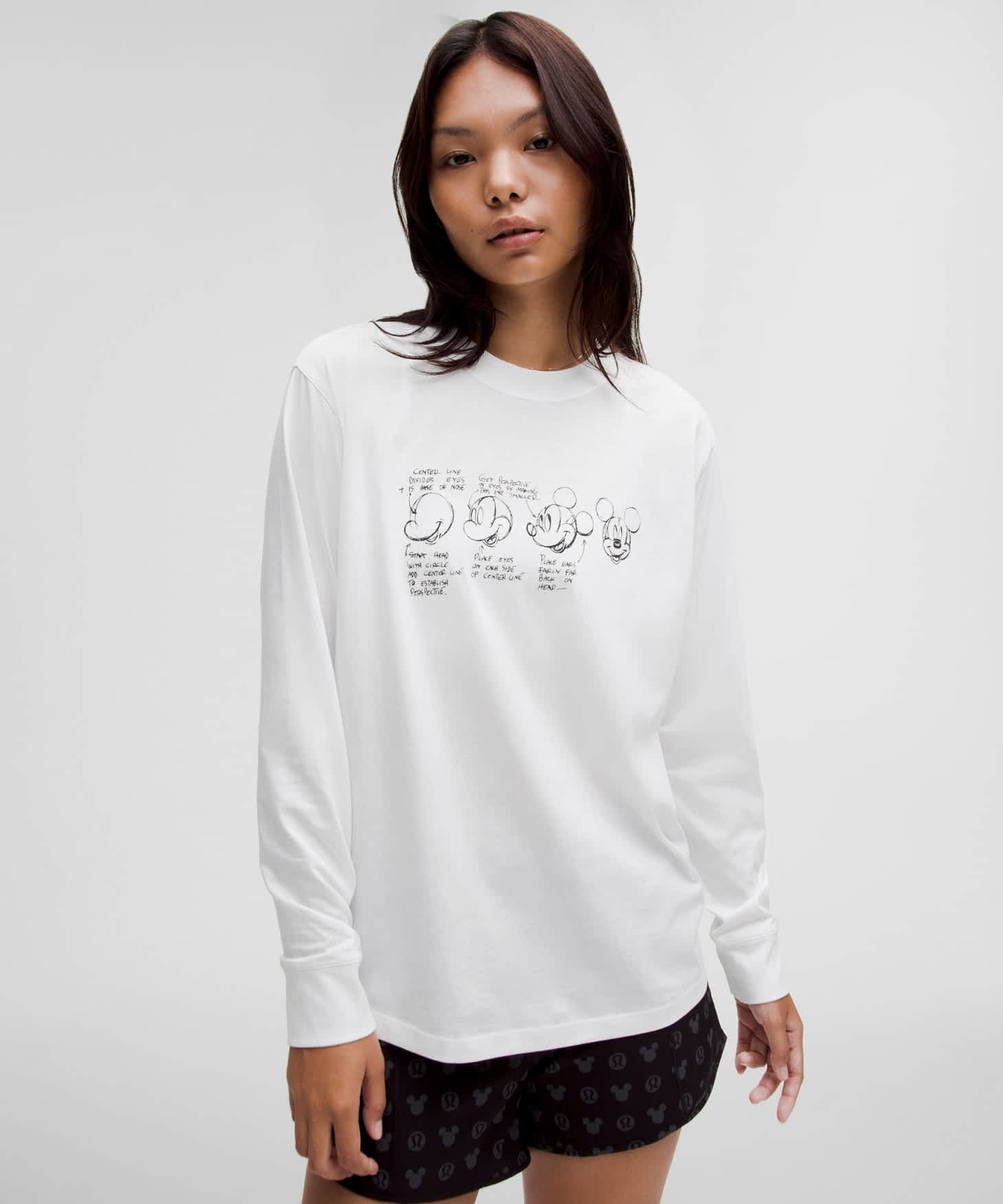 A woman wearing a white long sleeve t-shirt with a black illustration on it.