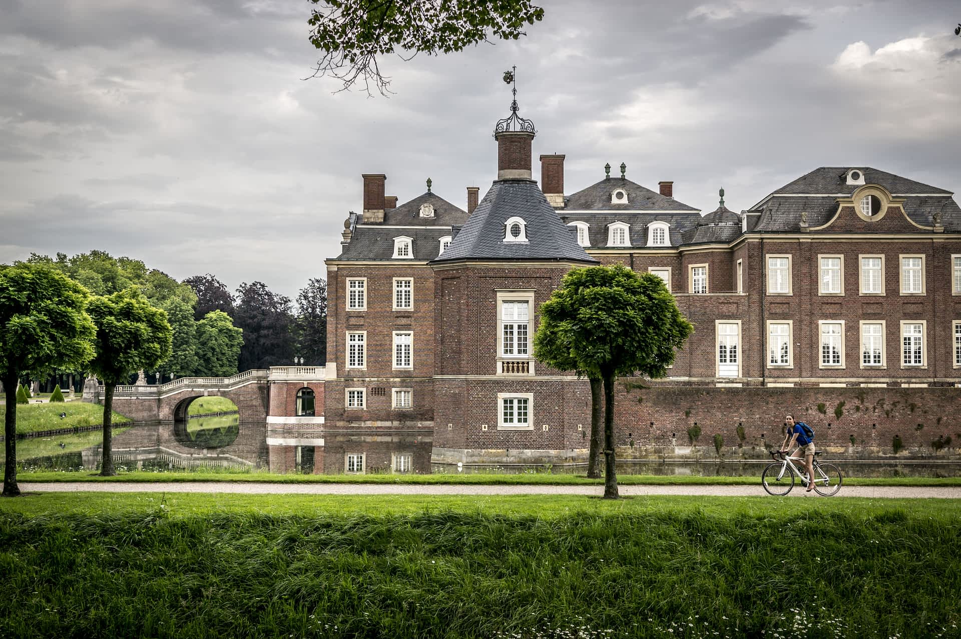 shutterstock410875936.jpg A cyclist rides a bike along a path beside a vast castle complex