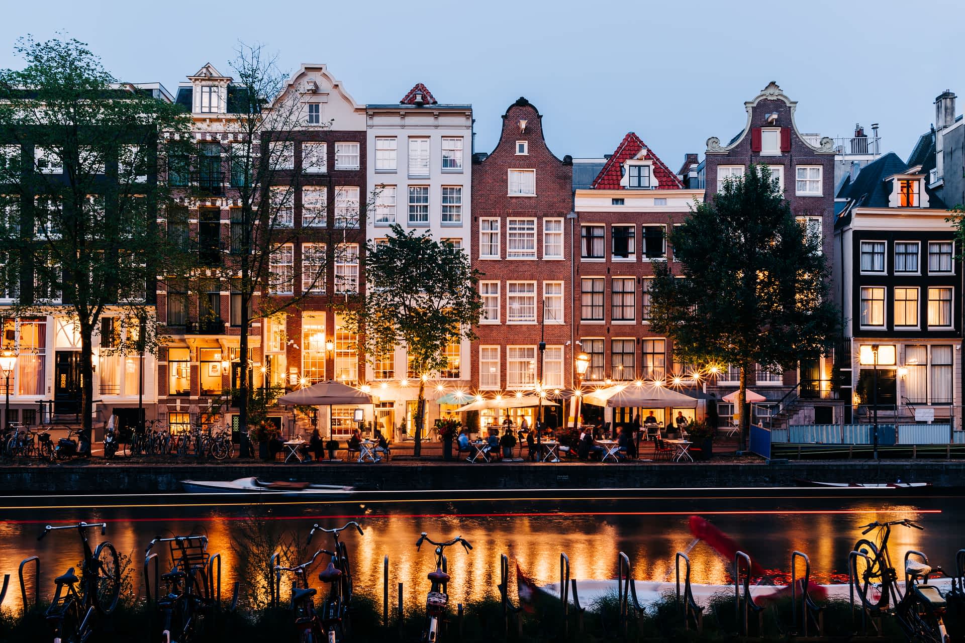 GettyImages-1337033260.jpg People sit at canalside tables outside bars and restaurants lit by string lights in the evening
