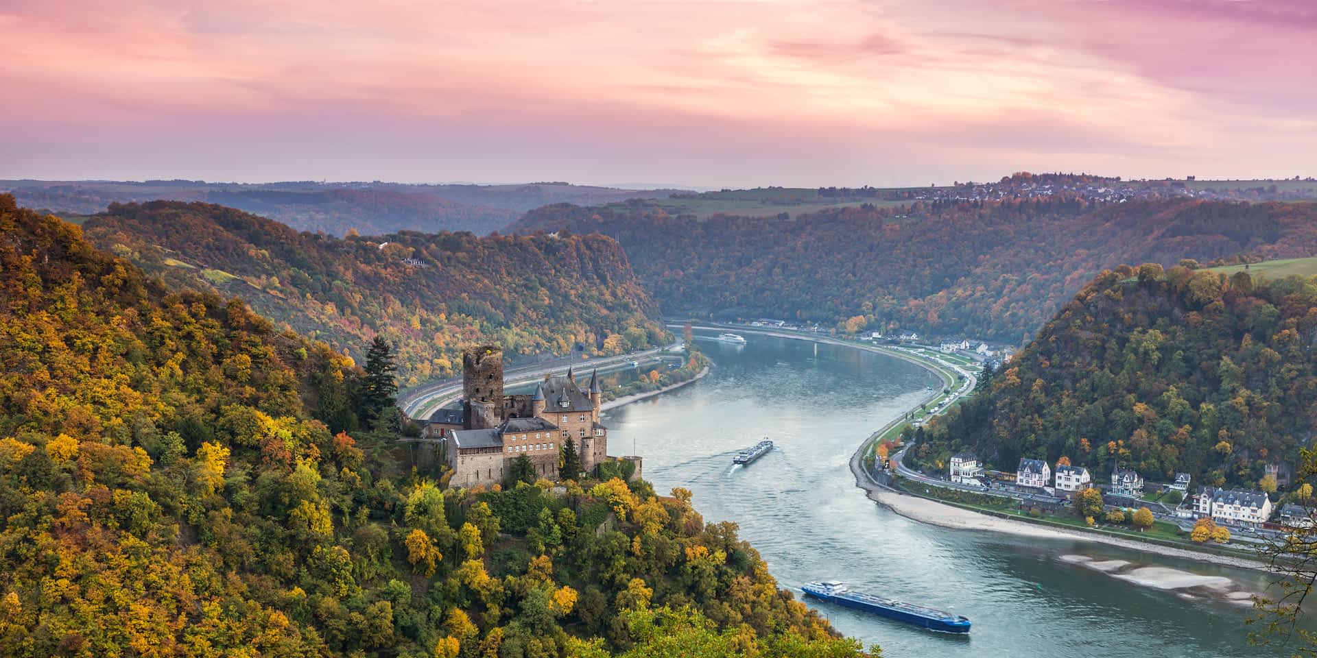 River cruise boats float down a village-lined river in Germany. 