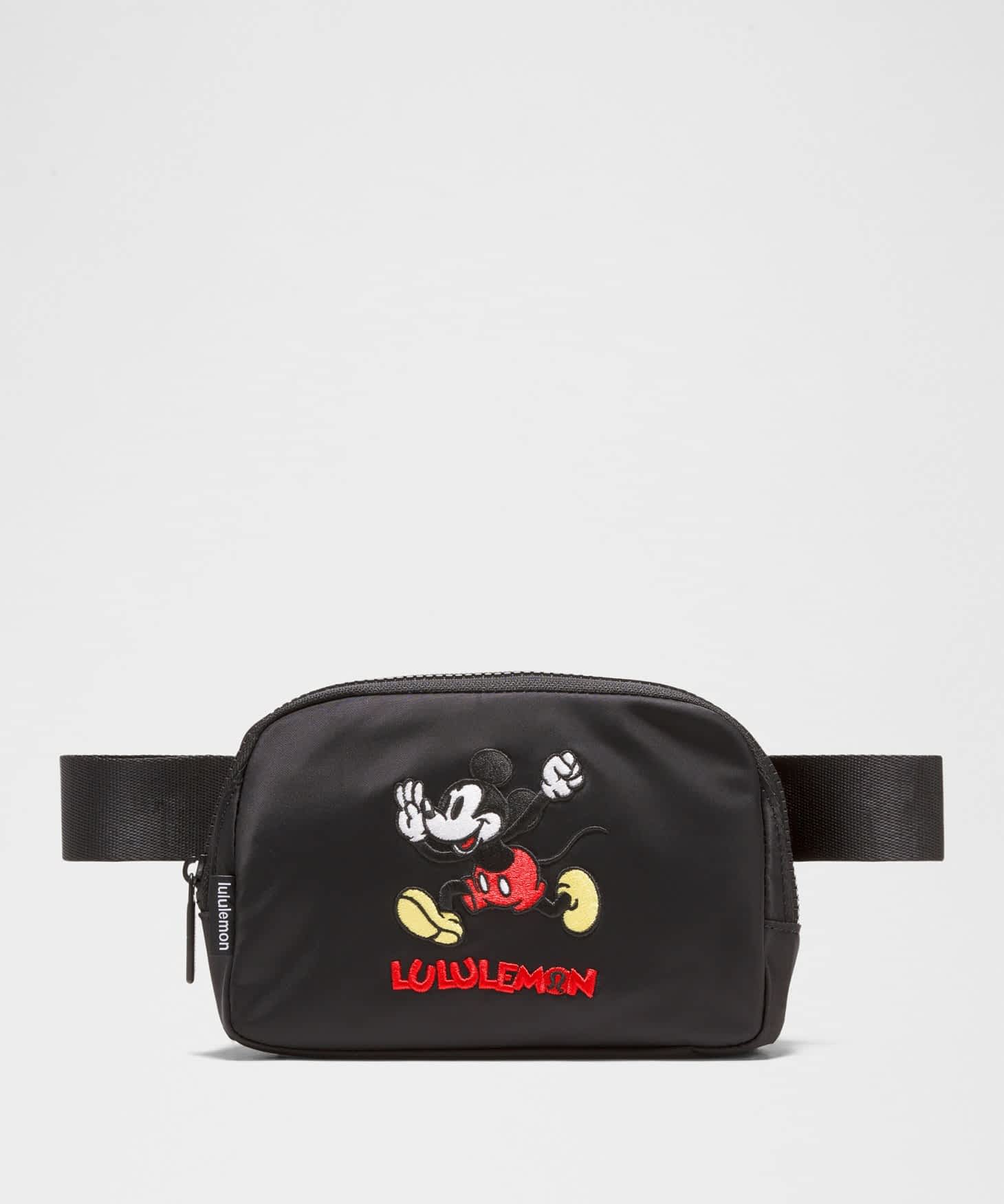 A black fanny pack with a patch of Mickey Mouse running on it.
