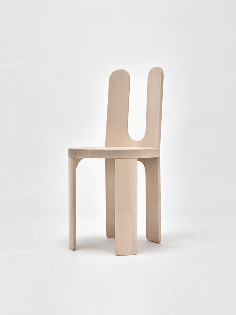 A modern chair with a light wood finish and a unique, dual backrest design.