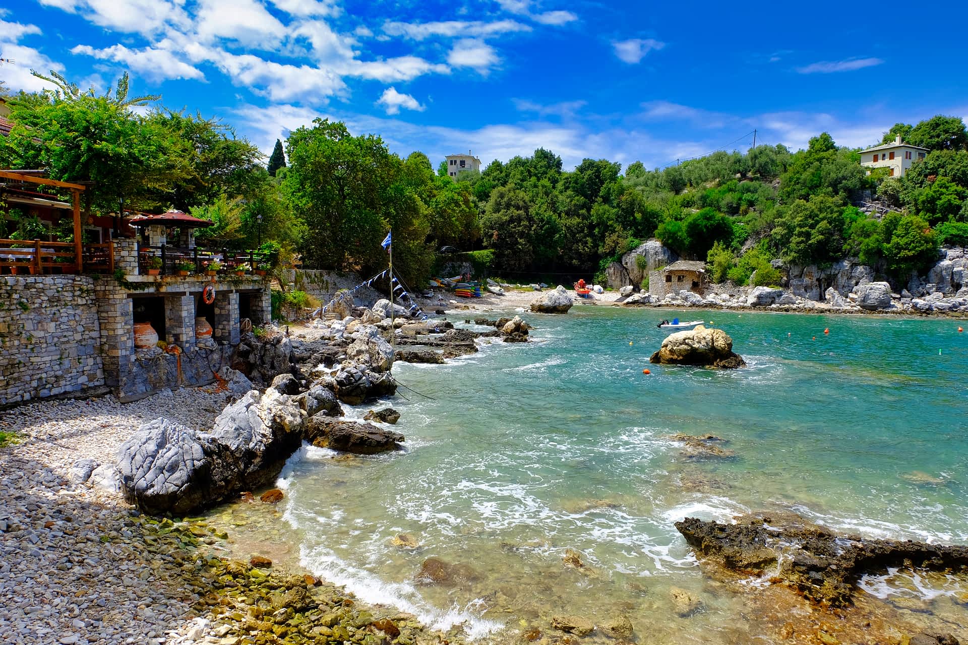 Stone buildings sit on the edge of a light blue coast. 