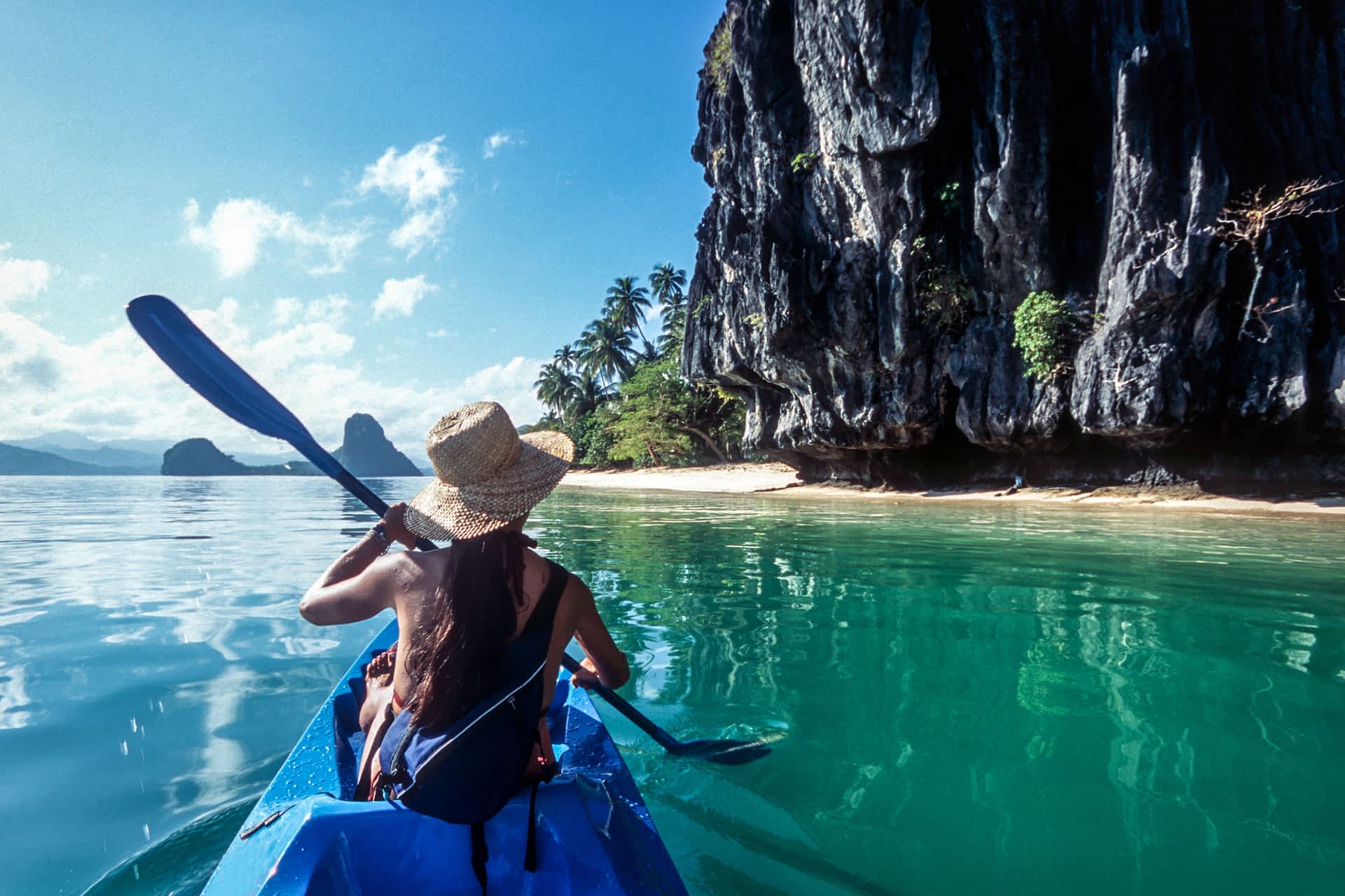 A kayaker beside a sandy beach at El Nido in the Philippines A kayaker approaches a hidden beach at El Nido, Philippines