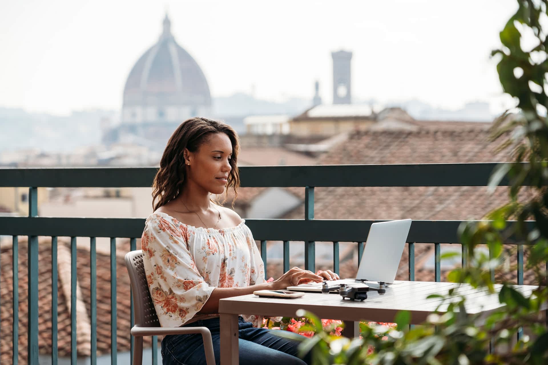 Florence, Italy A black woman at a laptop at a cafe in Florence with the city rooftosp in the background