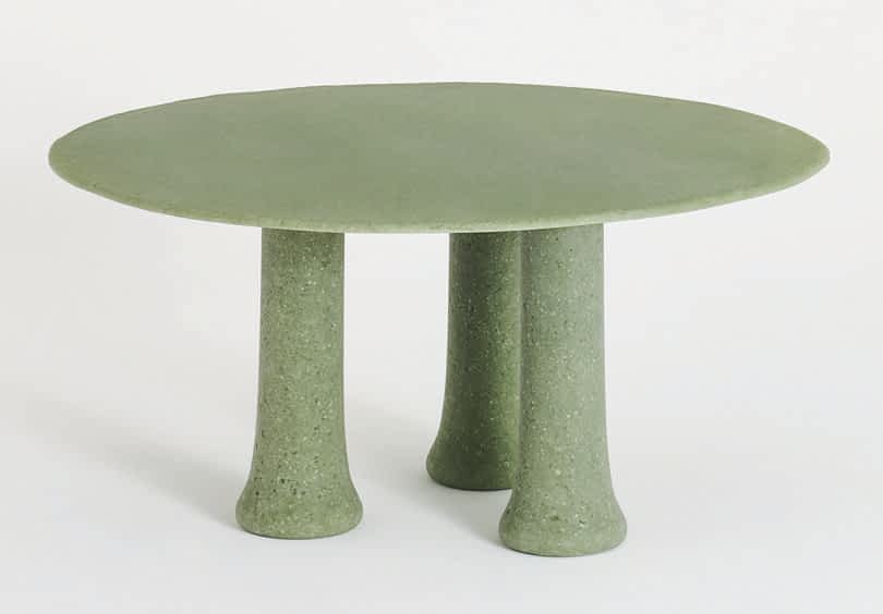 A round green table with a smooth top and three cylindrical legs on a white background.