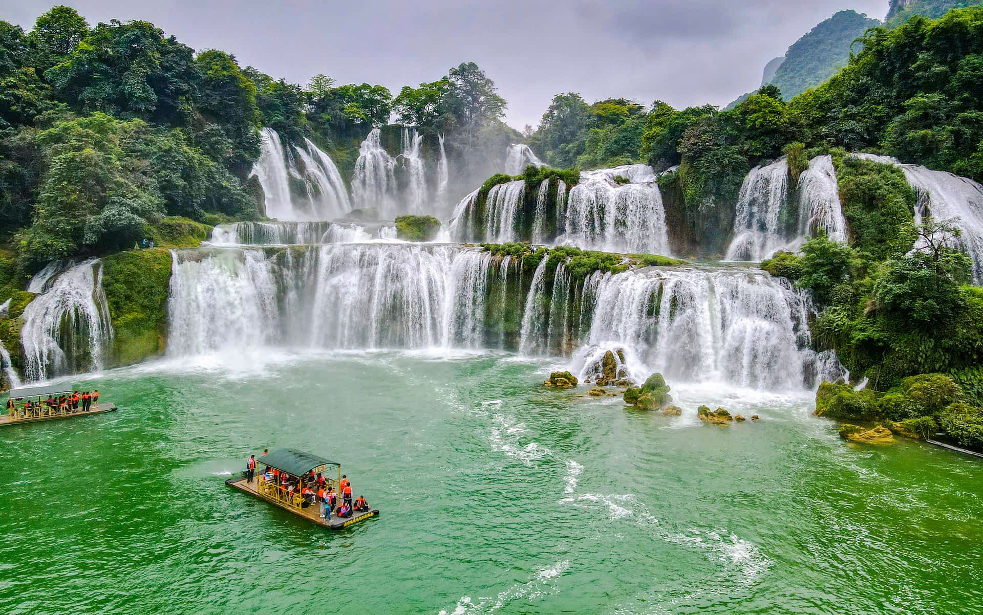 shutterstock2009607746.jpg A many tiered waterfall with a bamboo raft full of tourists in the pool