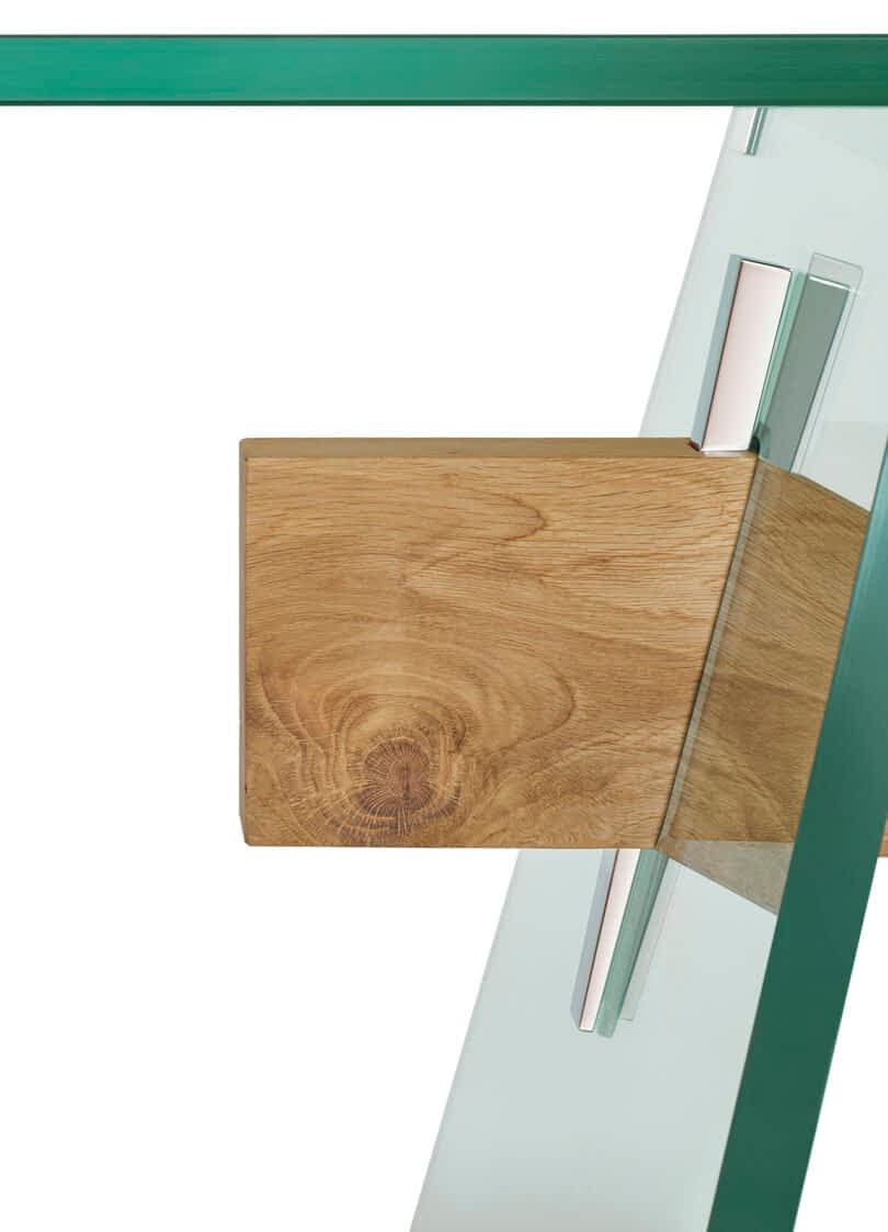 A wooden block attached to a glass dining table with metal brackets.