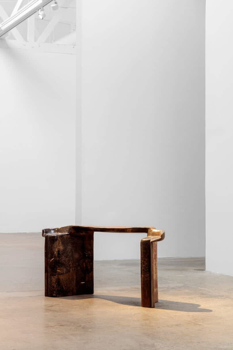 A unique, dark wooden chair with an asymmetrical design by Vincenzo De Cotiis is placed in an empty, well-lit white gallery space.