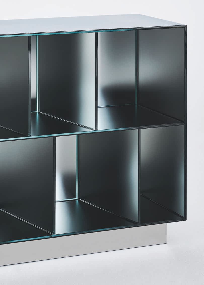 Detail of a modern metal storage unit with a geometric design featuring multiple square and rectangular compartments, positioned against a plain white background.