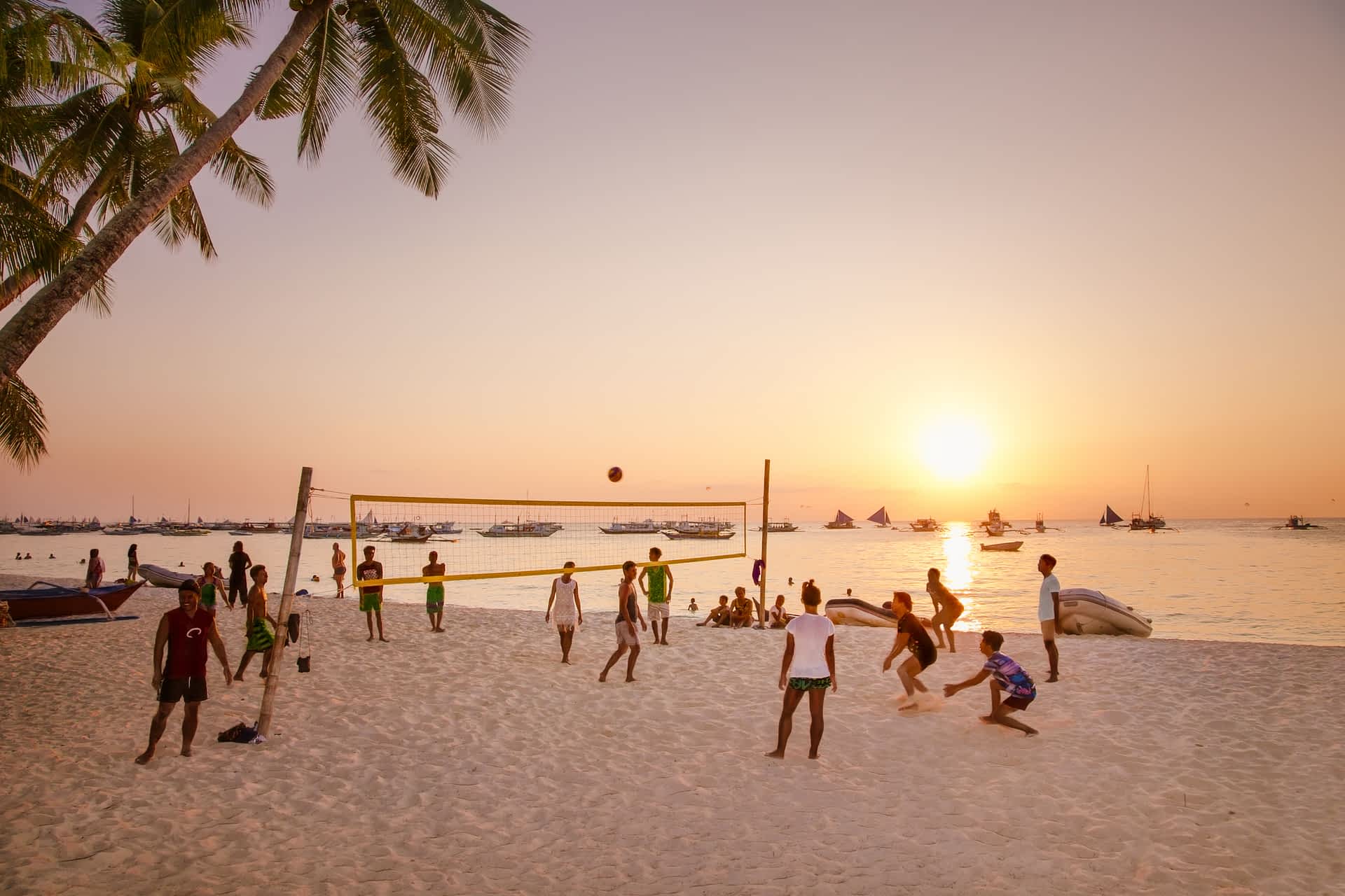 Beach volleyball at sunset on Boracay Island A group of people play volleyball as the sun sets at White beach, Boracay Island.