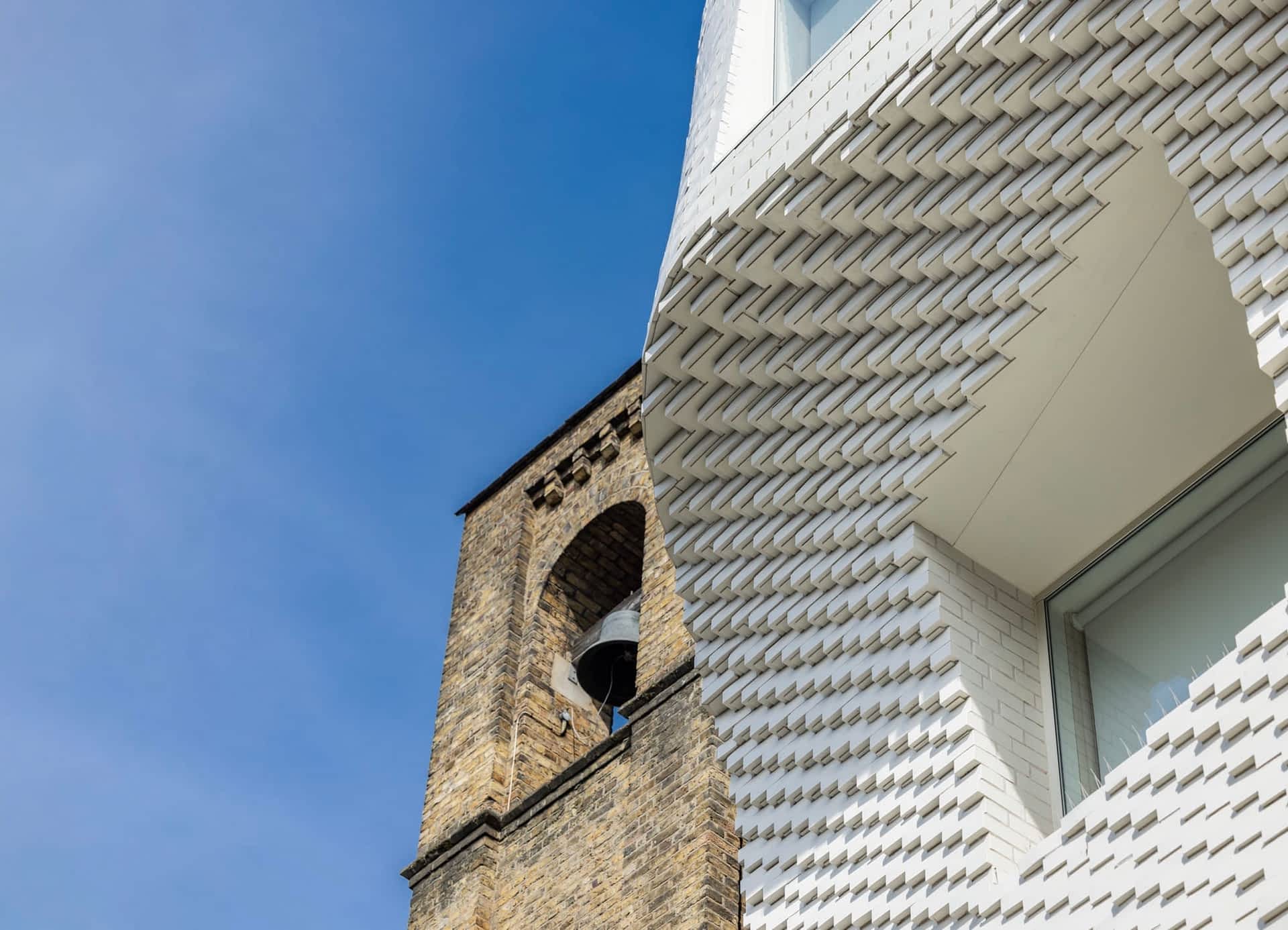 a detail of a white brick facade viewed from the ground, showing a concave form and numerous step-like patterns of bricks