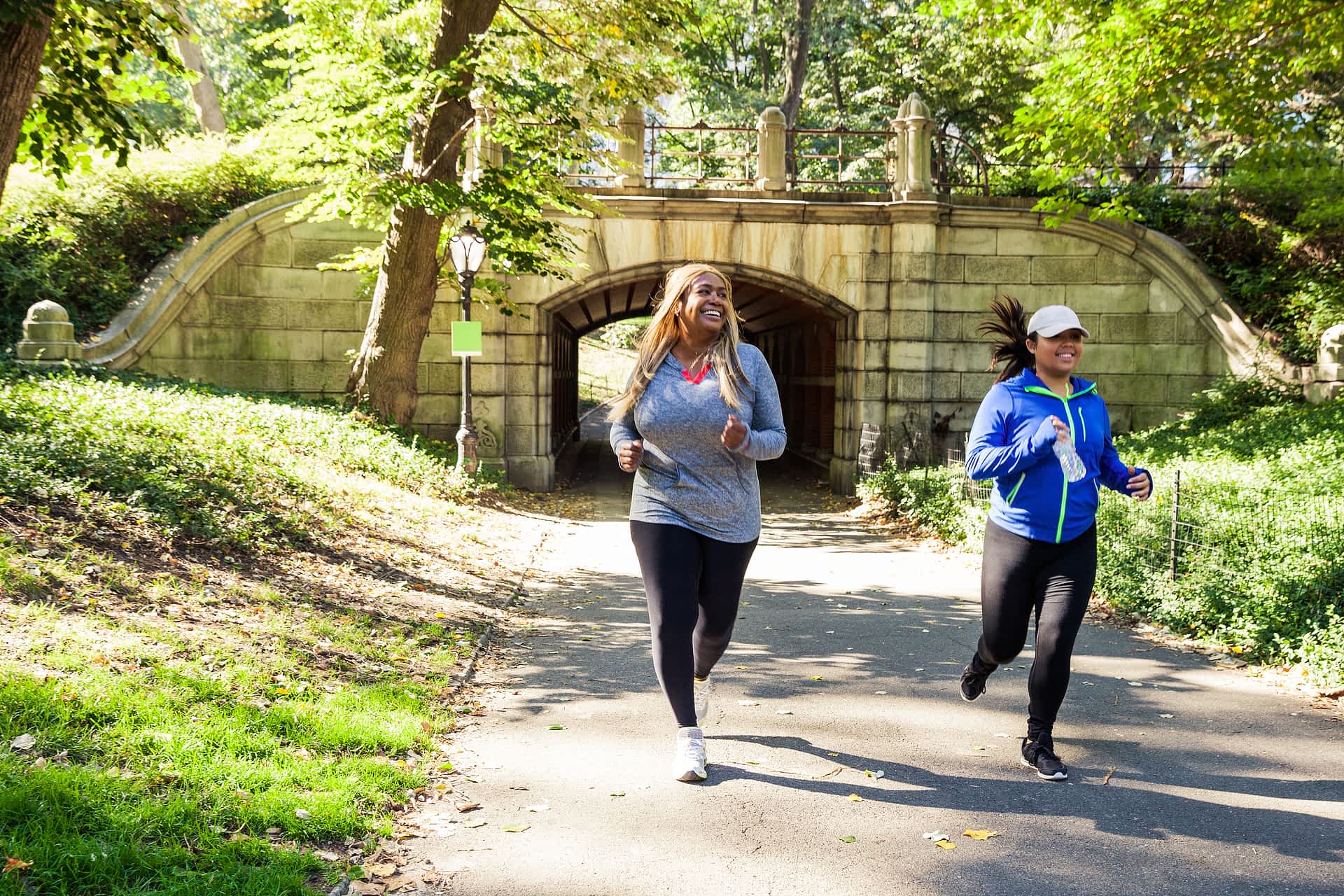 runners-in-central-park-new-york.jpg Two women emerge smiling from a tunnel under a decorative bridge as they run on a path in Central Park, New York.