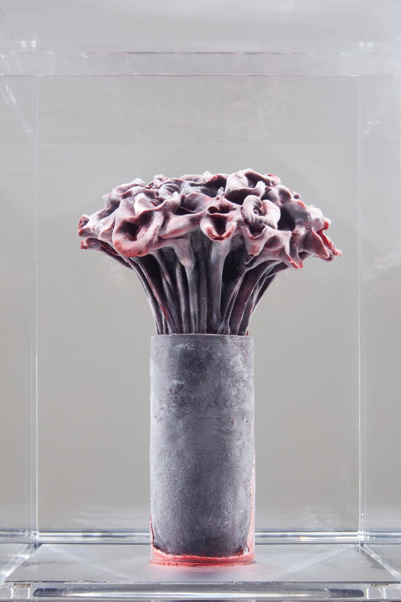 a bouquet of calla lilies in a simple vase, frozen solid inside of a plexiglass case