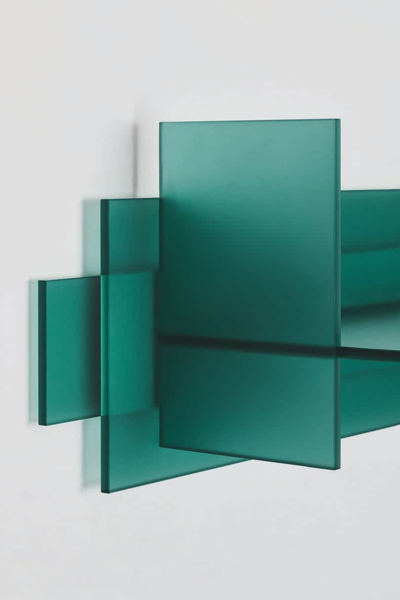 Detail of a minimalist green glass table displayed against a plain background.