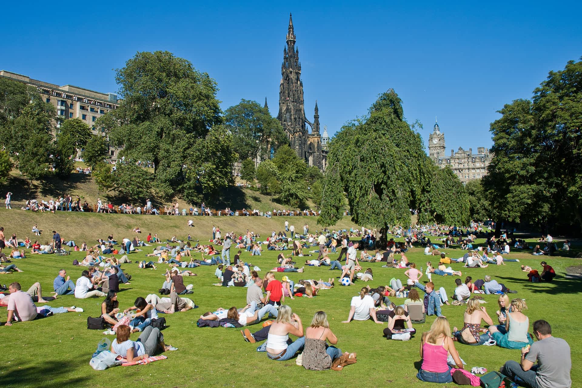 The Princes Street Gardens are an Edinburgh landmark. The Princes Street Gardens full of people with the Scott Monument behind on a sunny summer day.