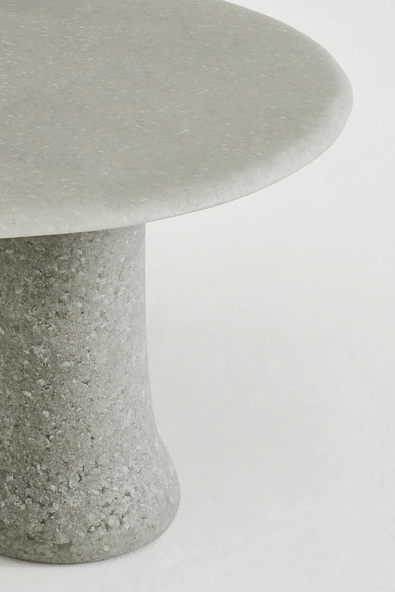 Detail of round table with a smooth top and cylindrical legs on a white background.