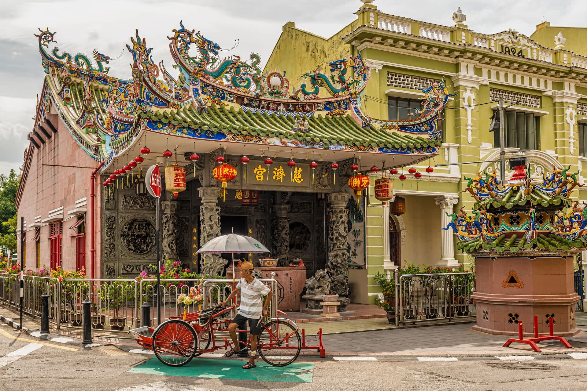 shutterstockRF1135709363.jpg A man stands by a rickshaw outside a temple with Chinese-style red lanterns