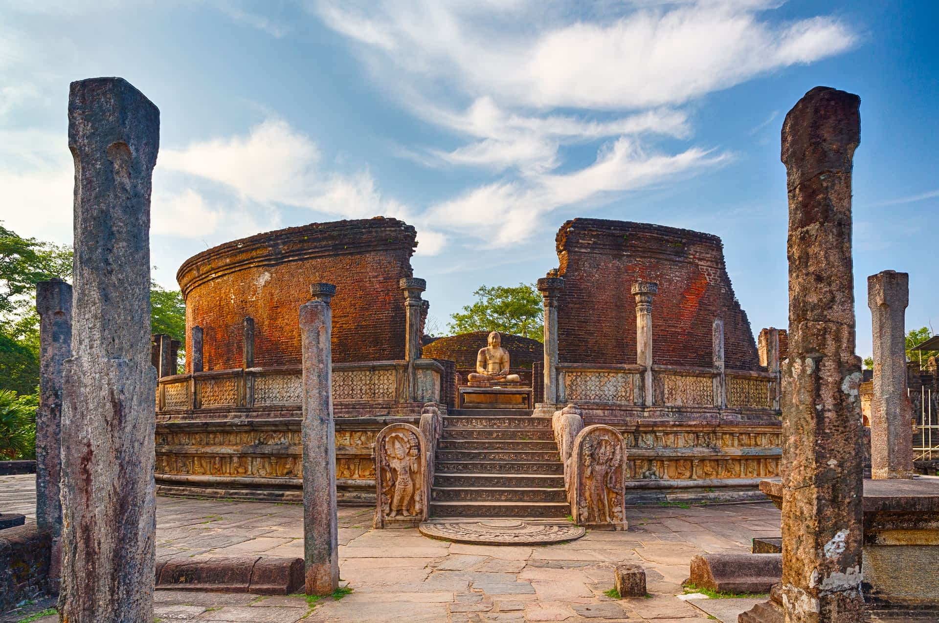 Polonnaruwa, Sri Lanka The crumbling brick walls and columns of a ruined temple with a buddha figure sat in the center