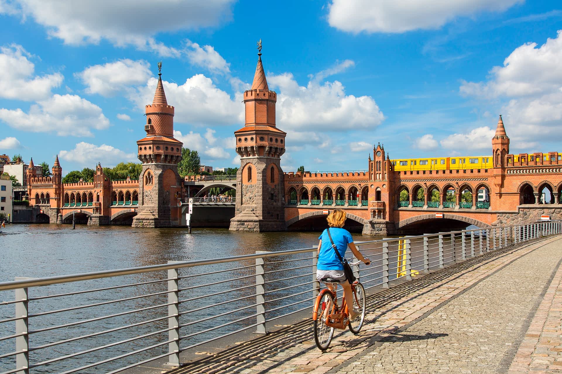 GettyImages-542715739.jpg A cyclist rides a bike along a riverside path towards a bridge where a train is crossing