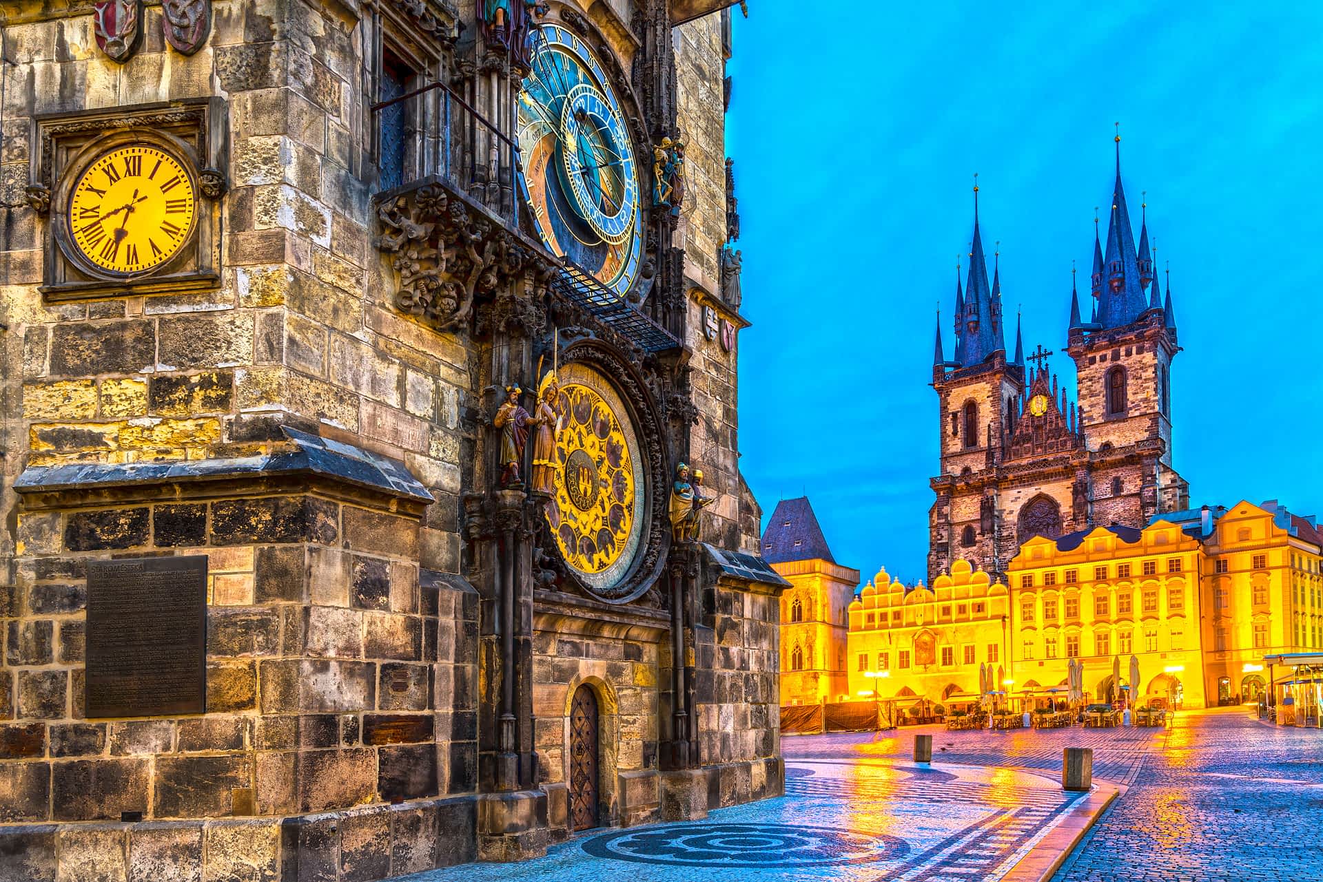 Old Town Square, Prague A damp city square in the evening with an ornate astronomical clock in gold and blue