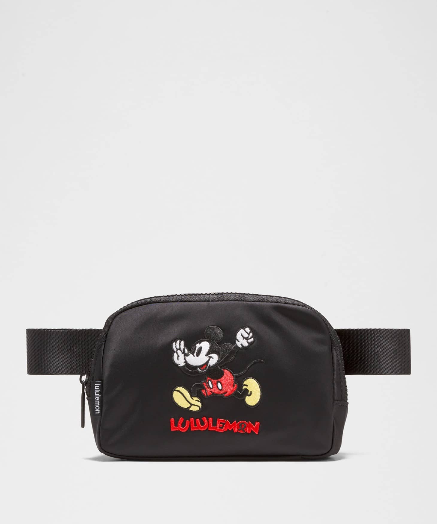 A black fanny pack with a patch of Mickey Mouse running on it.