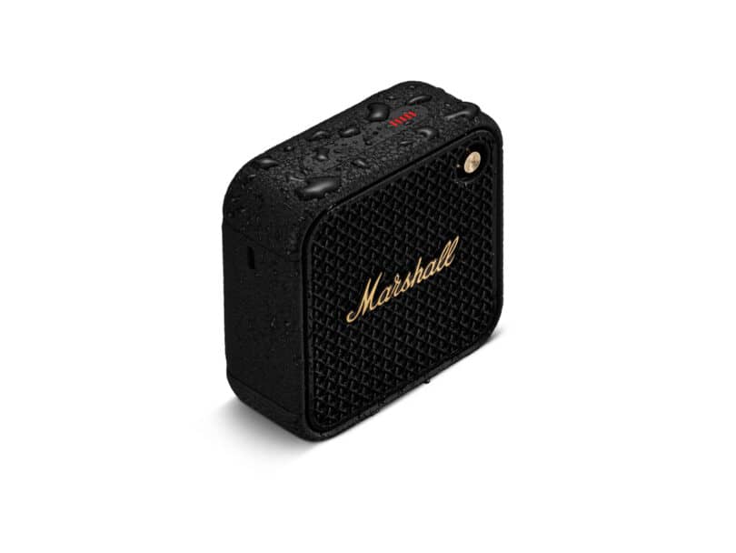 A black, rectangular Marshall speaker with water droplets on its surface, featuring a gold logo and control buttons on the top.