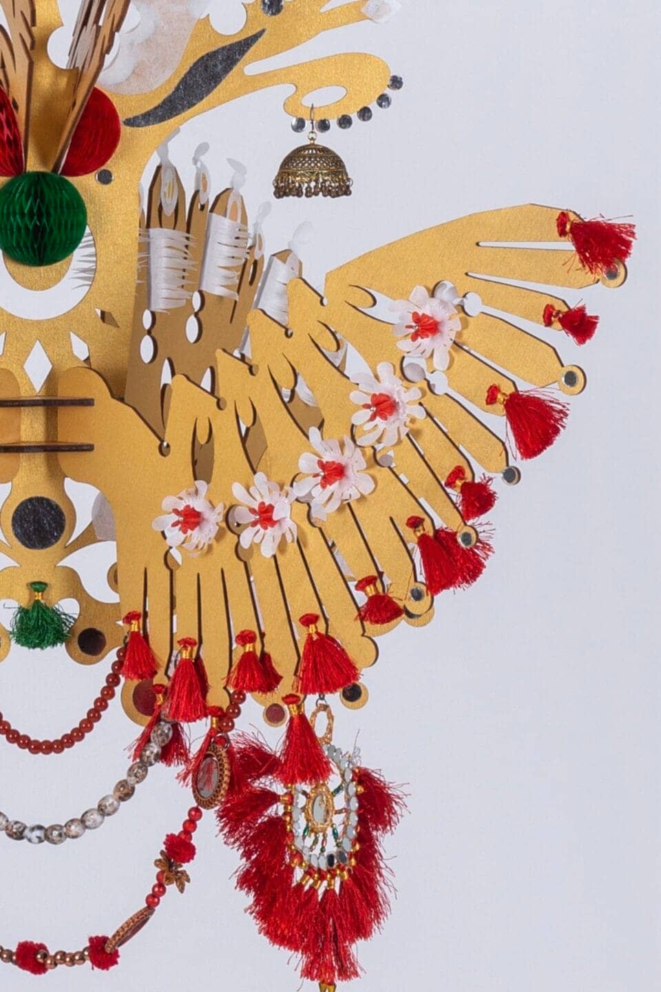 a detail of a suspended yellow, white, and red sculpture with wing-like details