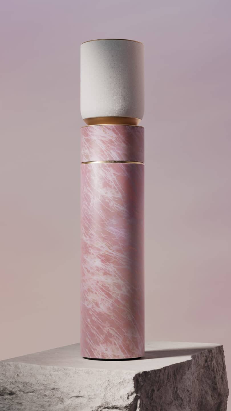 A tall, cylindrical object with a pink marble-like base and a white cylindrical top sits on a stone surface against a soft gradient background.