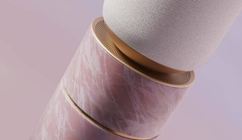 Close-up of a cylindrical speaker, featuring a textured fabric upper half and a marble-patterned lower half with gold accents, set against a gradient pink background.